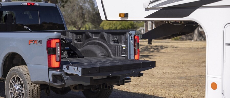 The tailgate down of a 2023 Ford Super Duty® truck being backed up to a 5th-wheel camper