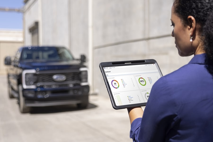 Woman using a tablet with a 2025 Ford Super Duty® Commercial truck in the background