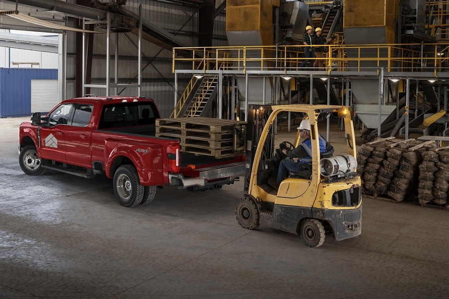 Man watching a forklift load cargo into the back of a 2025 Ford Super Duty® F-350® LARIAT® pickup