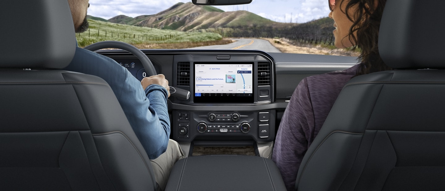 Man and woman sitting in a 2025 Ford Super Duty® F-350® LARIAT® pickup showing the centre display navigation screen
