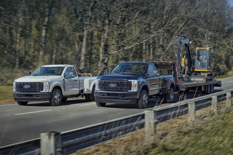 2025 Ford Super Duty® F-350® XL DRW in Oxford White and F-450® XL DRW in Antimatter Blue being driven on a paved road