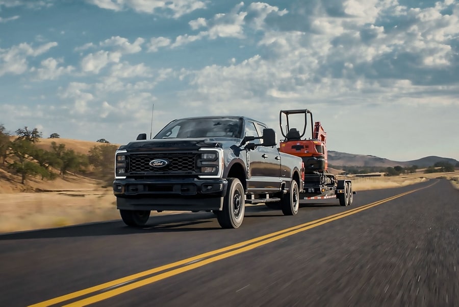 2025 Ford Super Duty® STX® pickup pulling a backhoe on a trailer