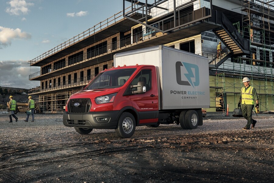 A 2023 Ford Transit® Chassis Cab parked at a construction site with a person approaching in safety gear