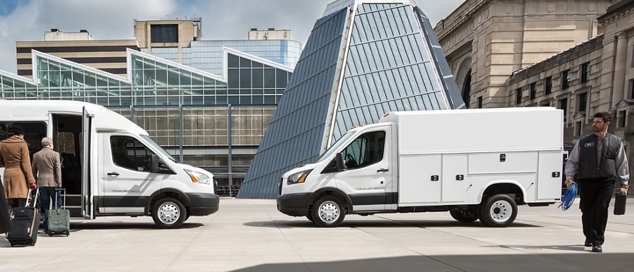 People near a 2024 Ford Transit® model with shuttle bus body and a 2024 Transit® model with aftermarket utility body