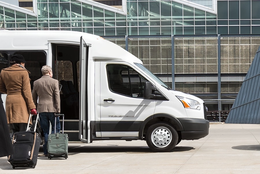 2024 Ford Transit® model with aftermarket shuttle bus body with passengers boarding