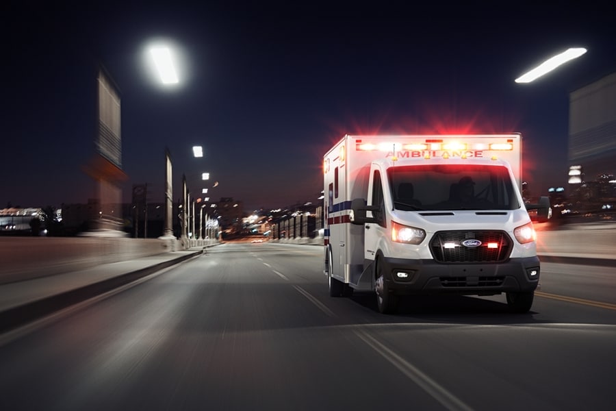 2024 Ford Transit® Cutaway model with Type III ambulance body being driven down a road at night