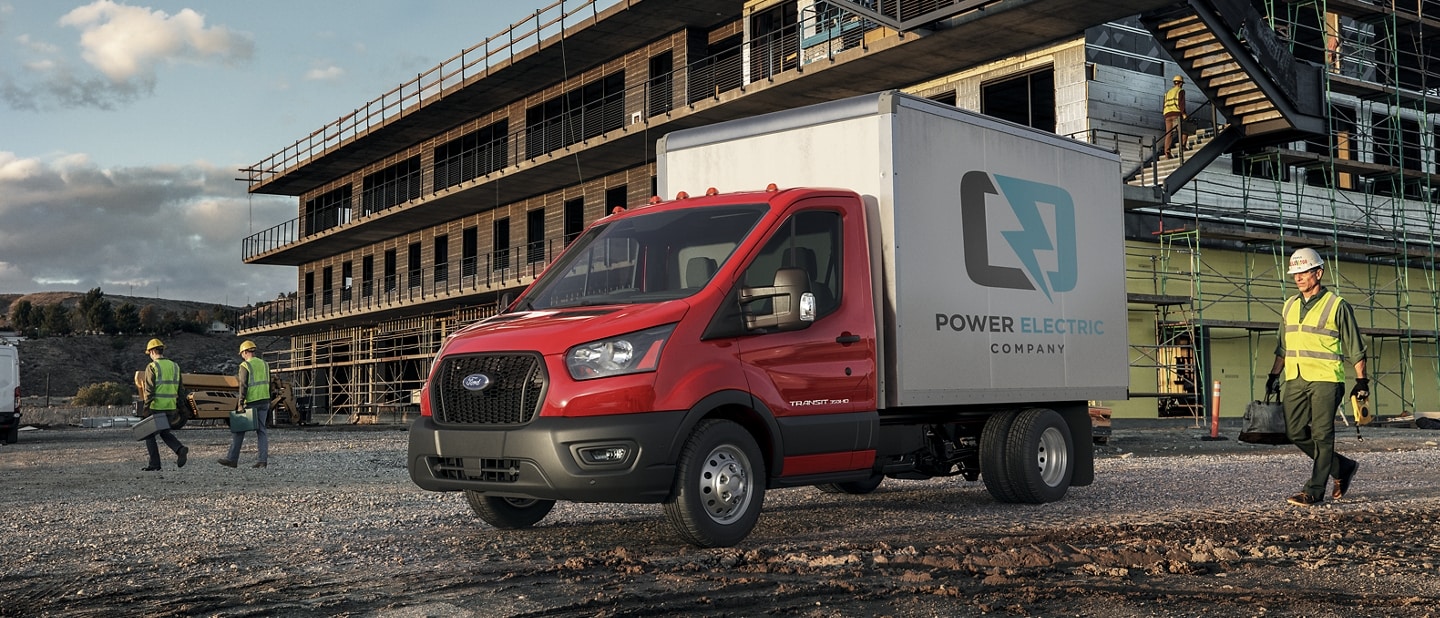 2025 Ford Transit® Chassis Cab model with box truck upfit parked at a construction site with three workers nearby