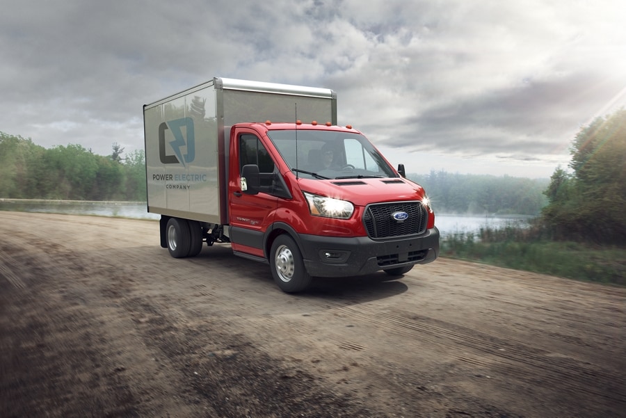 2025 Ford Transit® Chassis Cab model with box truck upfit being driven on a dirt road near a lake