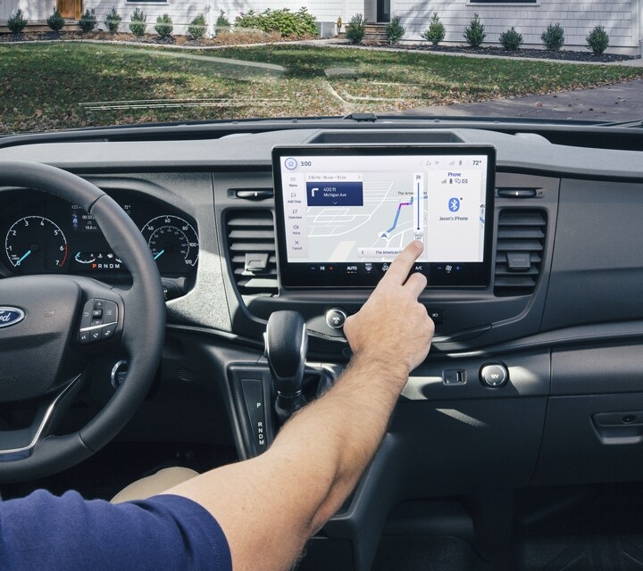 Driver using available SYNC® 4 with 12-inch multi-function display in a 2025 Ford Transit® model