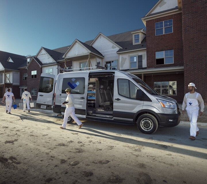A work crew unloading a 2023 Ford Transit® Van near a construction site