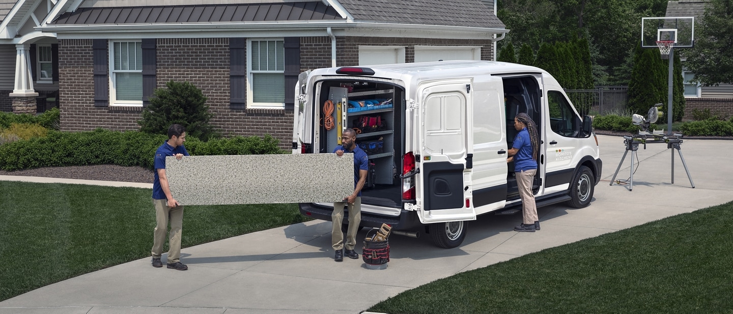 A 2023 Ford Transit® Van parked at a home with 2 men outside and a woman standing at an open side door