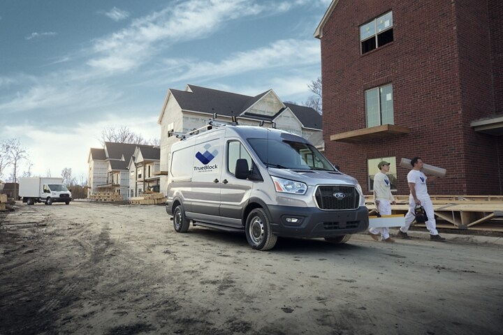 Two workers walking away from a 2023 Ford Transit® Van in Ingot Silver at a construction site
