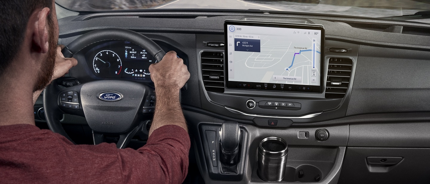 A man behind the wheel of a 2023 Ford Transit® Van using the Navigation System