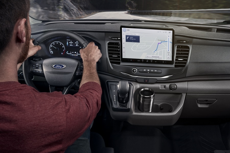 A man behind the wheel of a 2023 Ford Transit® Van using the Navigation System
