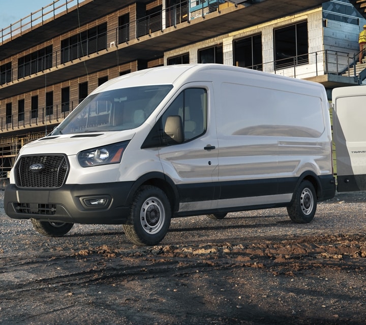 Two men talking at a job site with a 2023 Ford Transit® Van in the background with another man unloading equipment