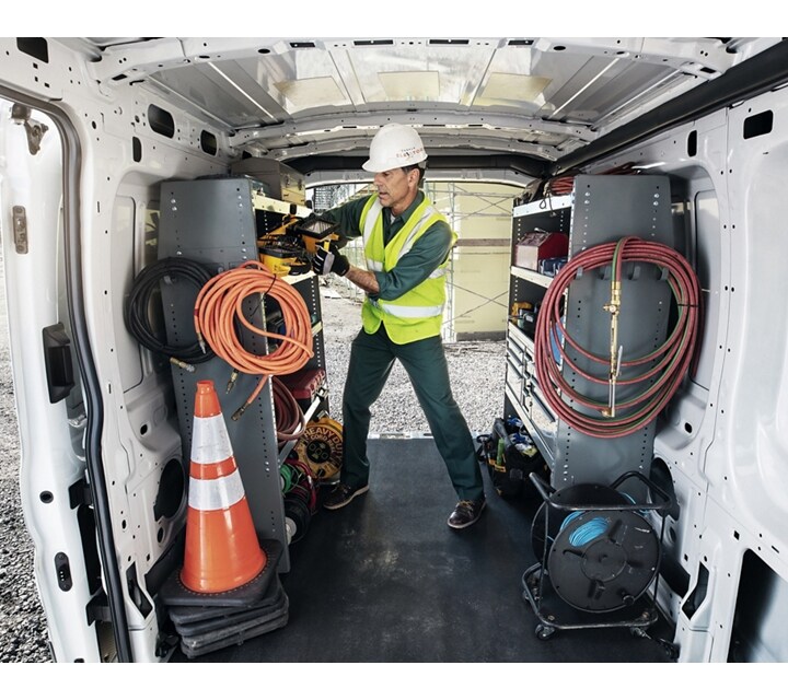 A person in the back of a 2024 Ford Transit® van with open cargo doors