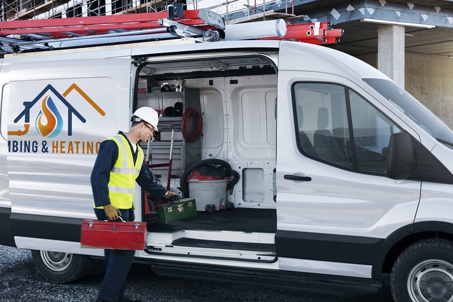 A worker loading a toolbox into the side of an open 2024 Ford Transit® van