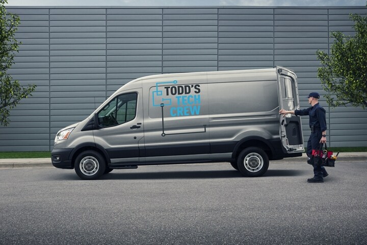 A workman opening the back of a 2024 Ford Transit® van carrying tool bag