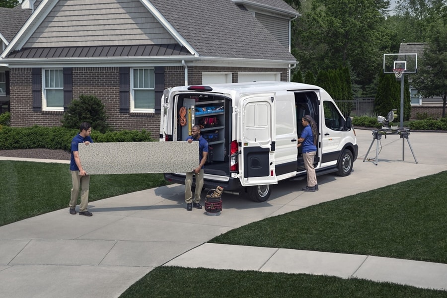 A crew of workers unloading a large slab of granite from a 2024 Ford Transit® van