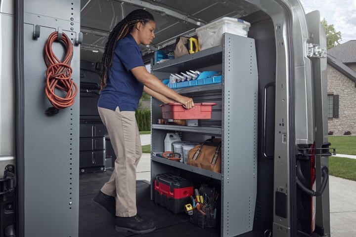 A woman standing in the back of a 2024 Ford Transit® van with a toolbox