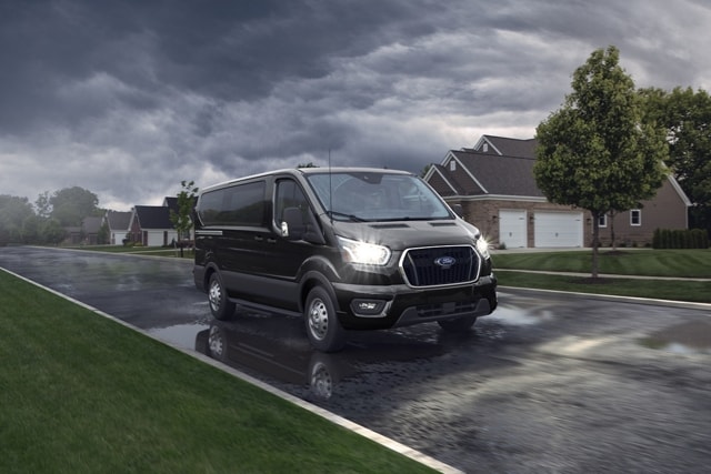 A 2024 Ford Transit® van is driving down a rainy street