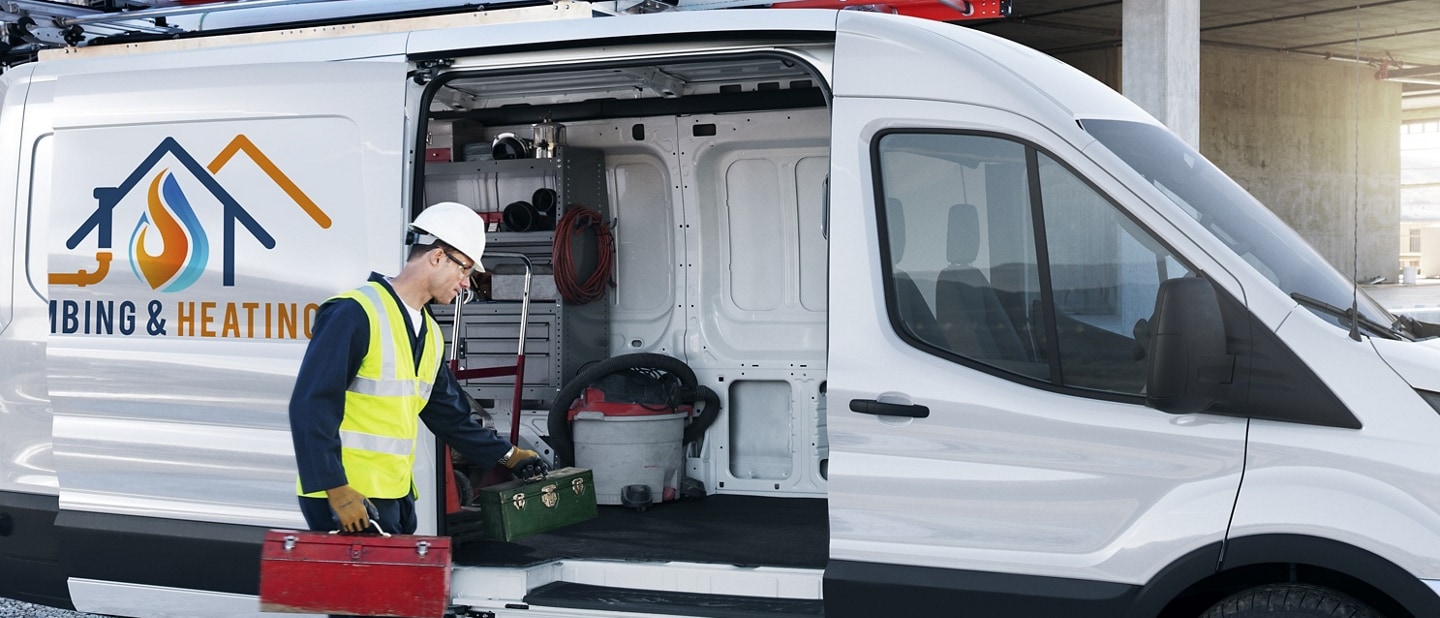 Man unloading tools from a 2025 Ford Transit® van with power-sliding door