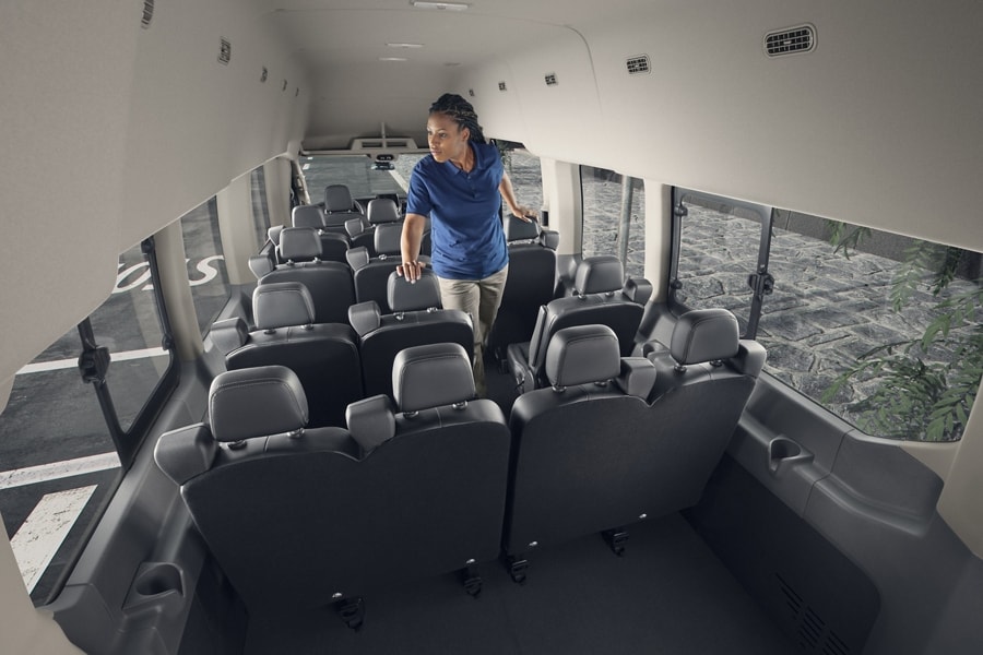 Woman walking through the interior of a 2025 Ford Transit® van with 15-passenger seating