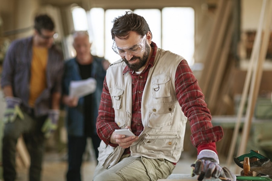 A working man inside a building looking at his smartphone