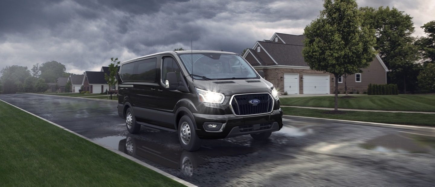 A 2025 Ford Transit® van is driving down a rainy street