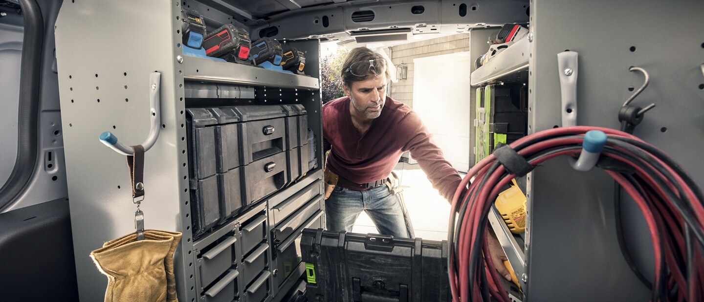 Interior view of a workman reaching into the back of a 2023 Ford Transit Connect Cargo Van