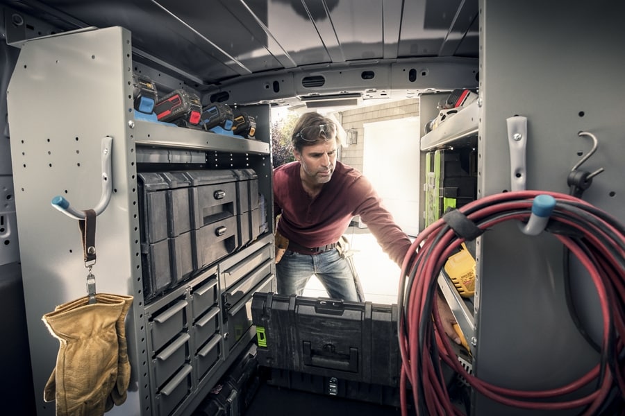 Interior view of a workman reaching into the back of a 2023 Ford Transit Connect Cargo Van