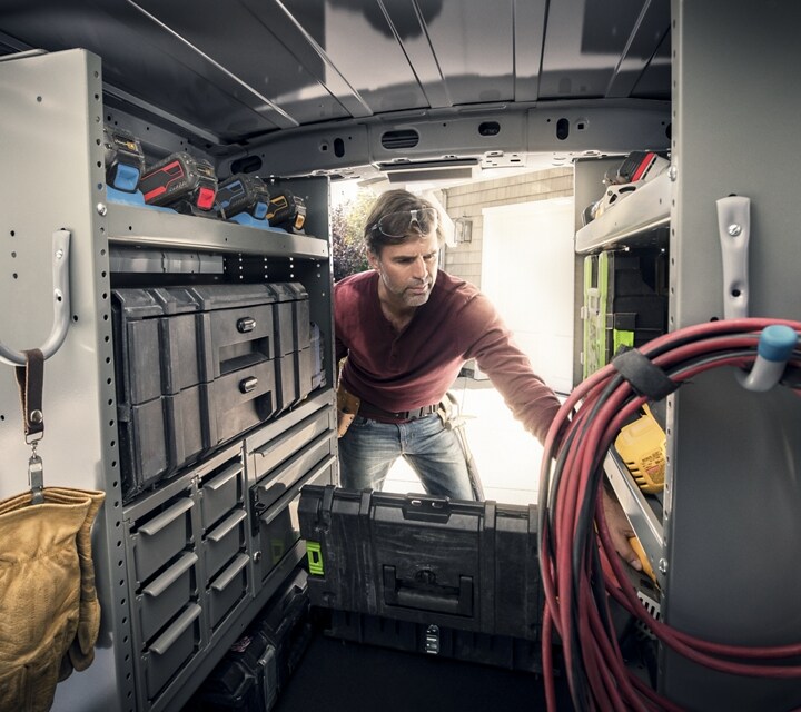 Interior view of a man reaching into the back of a 2023 Ford Transit Connect Cargo Van