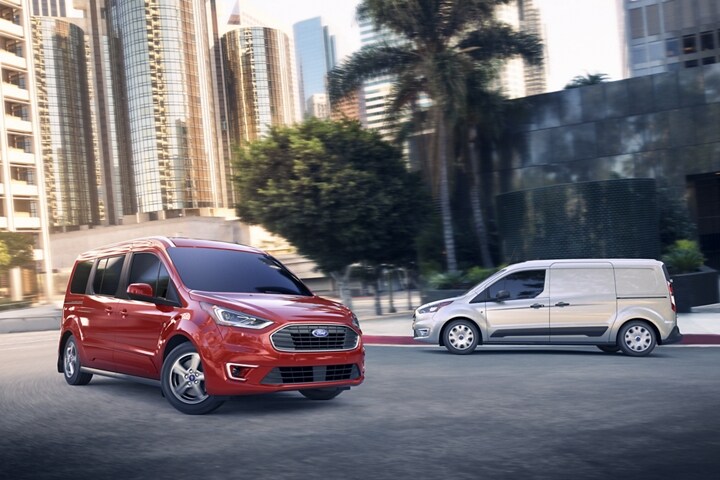A 2023 Ford Transit Connect Passenger Wagon in Race Red and a Transit Connect Cargo Van in Silver on the street