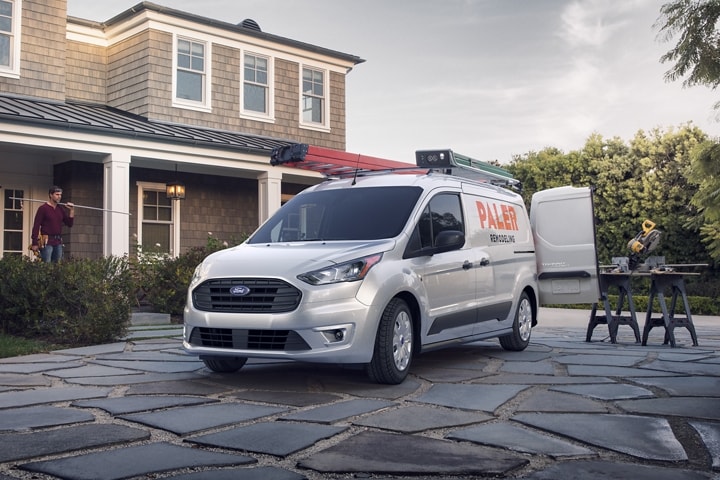 2023 Ford Transit Connect XLT Cargo van in Silver with available aftermarket business graphics parked in front of a home