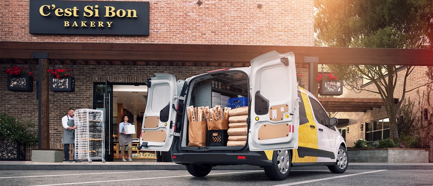 Swing-out rear cargo doors shown on the 2023 Ford Transit Connect Cargo Van parked in front of a bakery