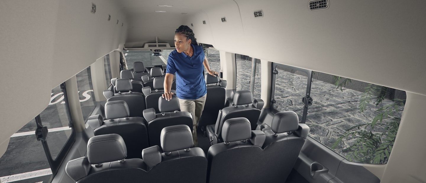 A woman standing in the interior of a 2023 Ford Transit® van with 15 seats