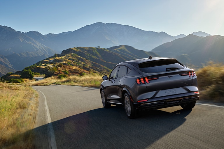 Rear view of a 2021 Ford Mustang Mach E Premium being driven along a mountain road